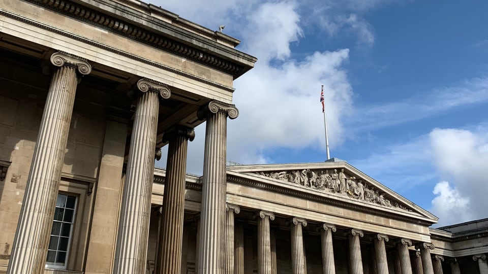 British Museum 南立面的爱奥尼柱廊与三角山花在云层下展开。