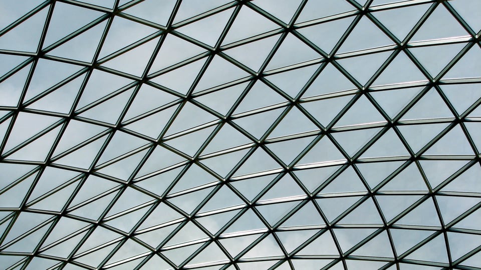 British Museum Great Court 的玻璃屋顶由深色钢框切成连续的三角网格。