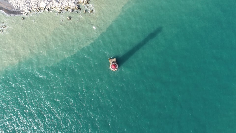 Beachy Head 红白灯塔立在浅绿色海面上，细长的影子斜伸向右上方。