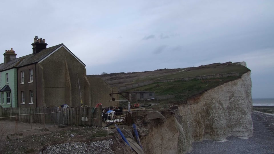 2009 年的 Birling Gap：海崖切面紧邻旧建筑与围栏，画面清楚呈现持续侵蚀的海岸关系。