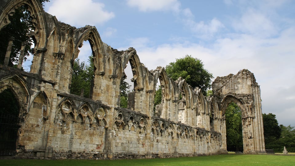 York Museum Gardens 内 St Mary's Abbey 的尖拱残墙沿草地延伸，窗洞与断裂墙顶清晰可见。