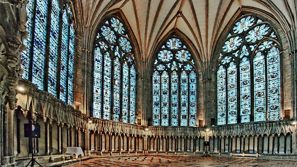 York Minster Chapter House 的拱顶从四周墙面向中央汇合，彩色玻璃窗环绕八角形空间。