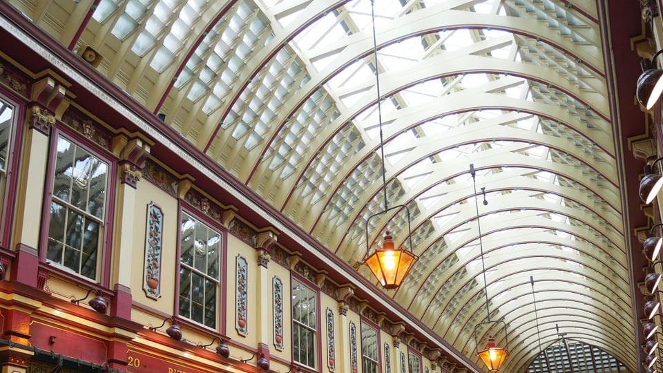 Leadenhall Market 西侧通道的彩绘铸铁、拱形玻璃顶与悬灯沿街巷向远处延伸。