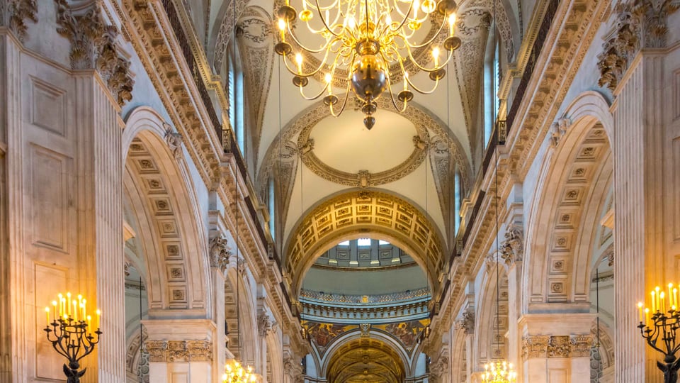 St Paul's Cathedral 中殿的柱列与拱顶沿中央轴线通向穹顶下方，枝形灯从两侧排开。