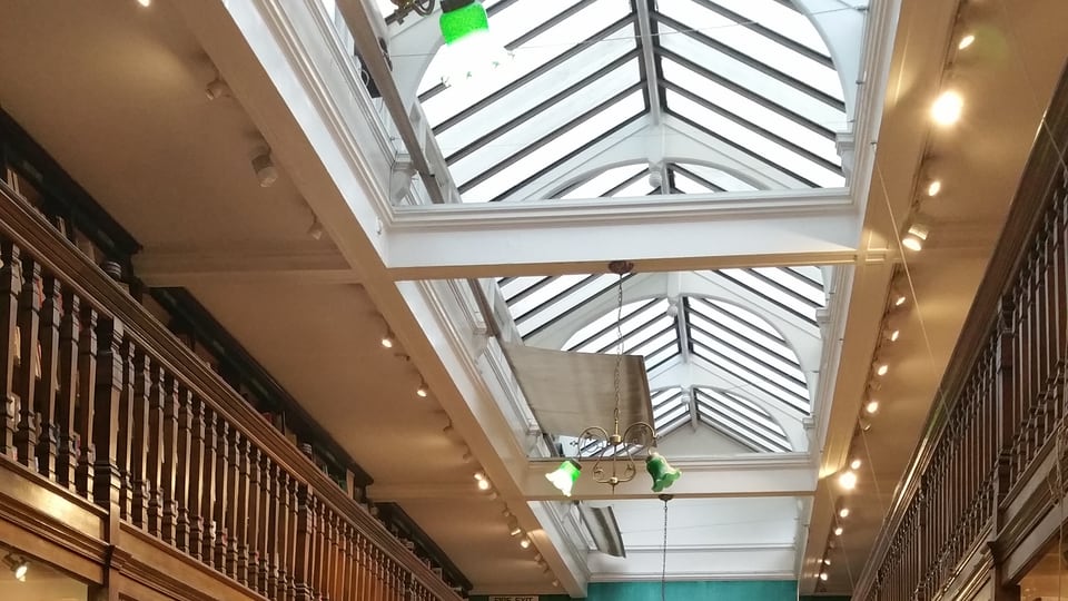 Daunt Books Marylebone 的玻璃屋顶跨在深色木质回廊上方。