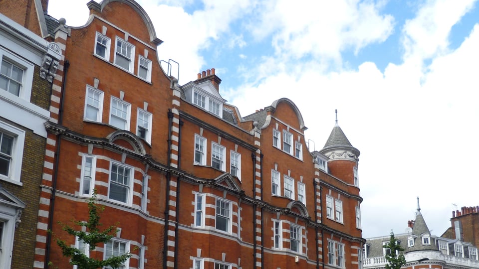 Marylebone High Street 上方的红砖街墙连续展开，白色窗框、曲线山墙与角塔构成鲜明轮廓。